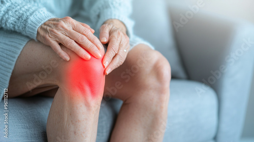 Elderly woman suffering from knee pain with red glowing area, highlighting joint inflammation photo