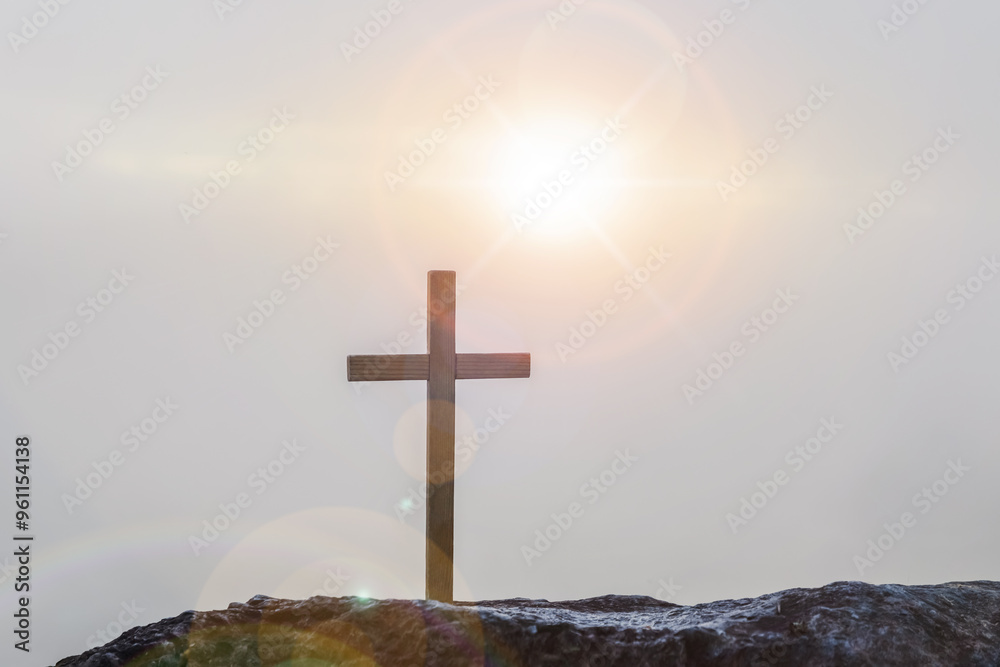 Silhouettes of crucifix symbol on top mountain with bright sunbeam on the colorful sky background Silhouettes of crucifix symbol on top mountain with bright sunbeam on the colorful sky background