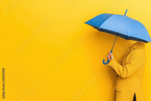 A woman holding a bright blue umbrella standing against a plain yellow background in a simple and colorful image
