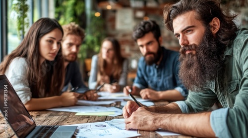 A diverse group of five individuals gathers at a wooden table in a cozy cafГ©, actively discussing ideas and taking notes while working on creative projects in the early afternoon light
