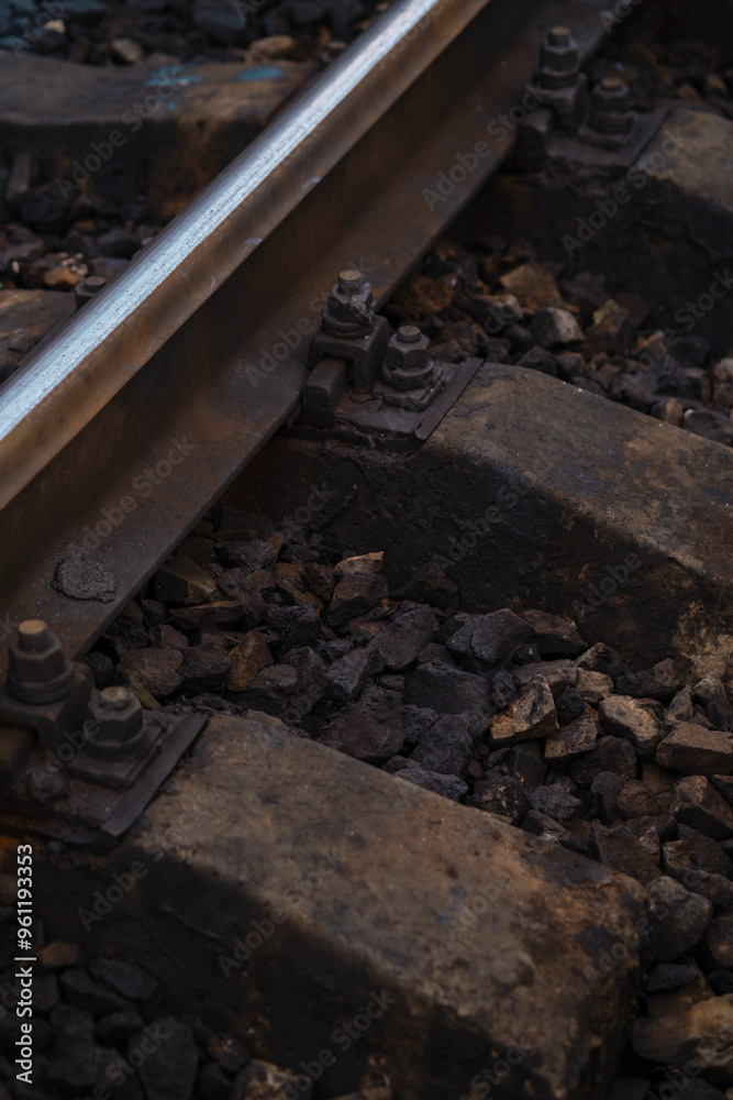 Close-up view of weathered railway tracks with rusted bolts and gravel during golden hour light Close-up view of weathered railway tracks with rusted bolts and gravel during golden hour light
