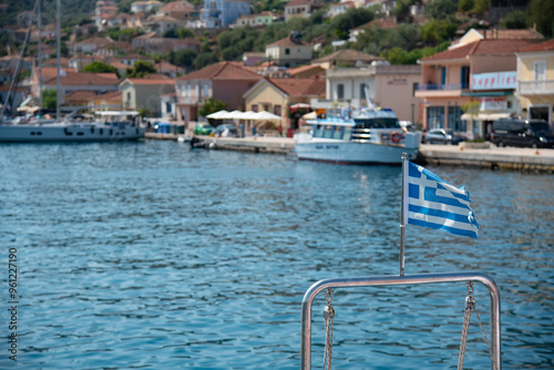 Greek flag waving. Boat approaching vathi village in Ithaca Greek Island in the ionian sea. photo