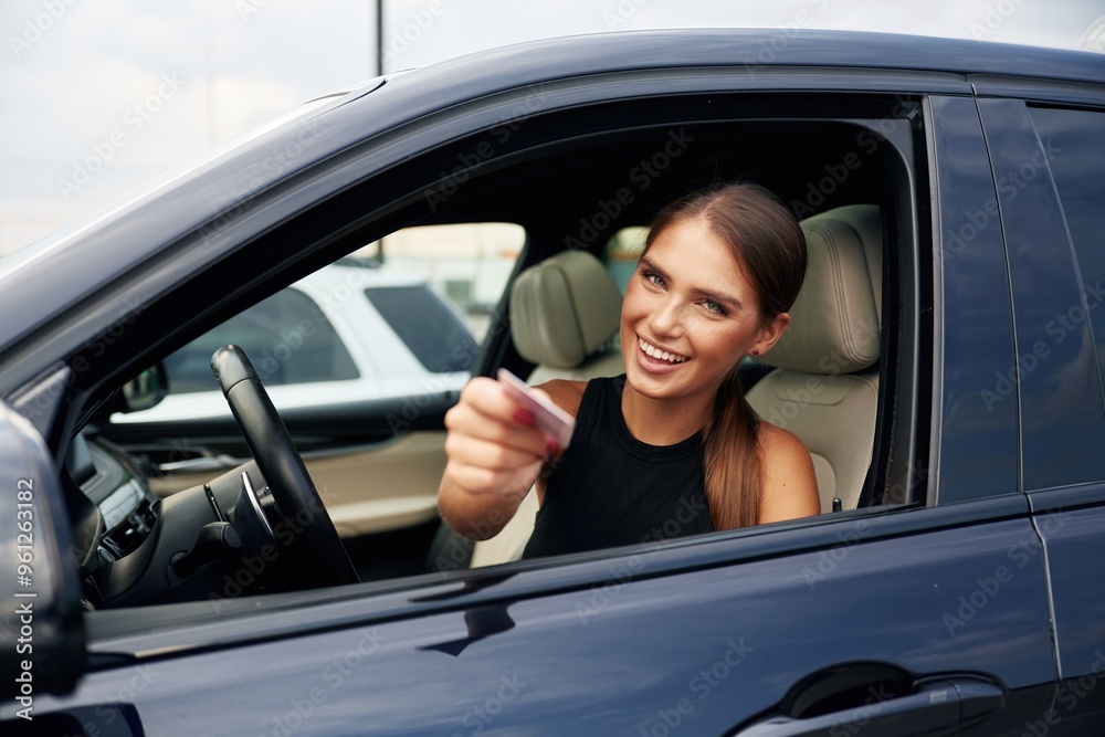 Showing off with the driver's license. Woman is sitting in the car Showing off with the driver's license. Woman is sitting in the car