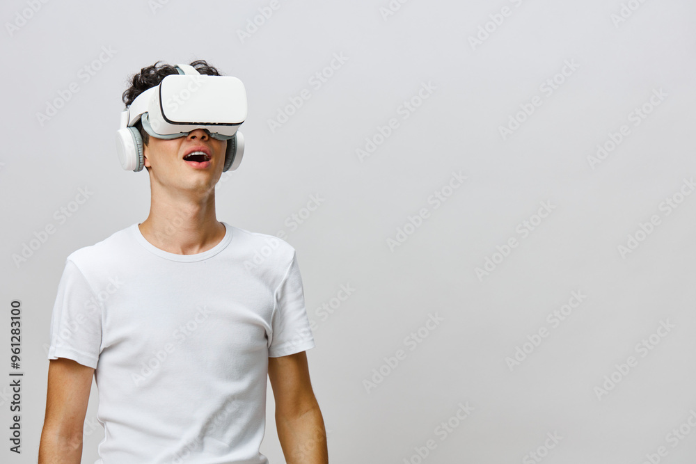 Virtual reality experience, male user with VR headset, amazed expression, modern technology, immersive entertainment, bright background, casual attire, tech enthusiast, innovation enjoyment