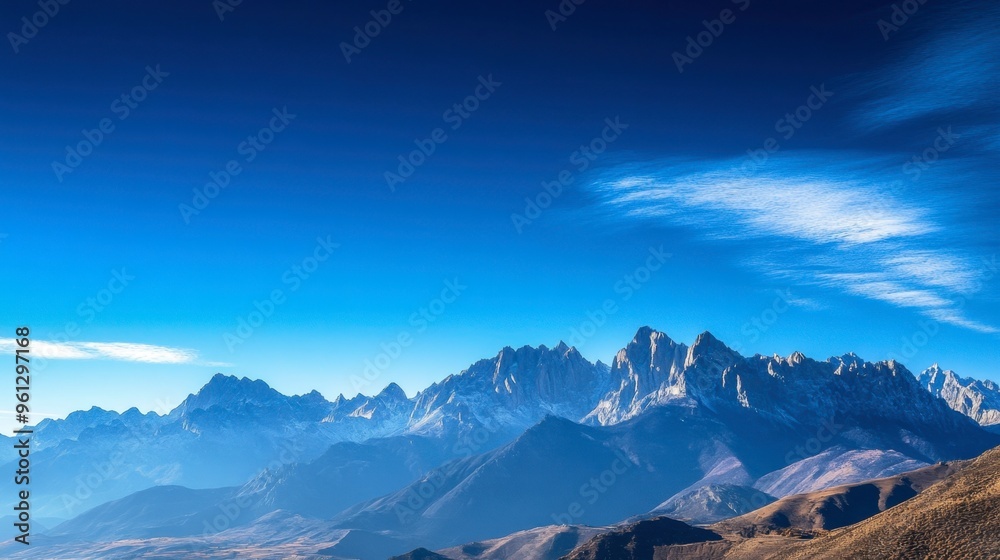 Obraz premium A clear sky over a mountain range, with peaks sharply defined against the bright blue background.