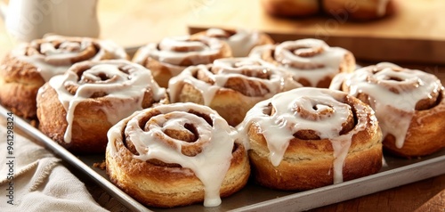 A platter of freshly baked cinnamon rolls with cream cheese icing, placed on a rustic kitchen counter photo