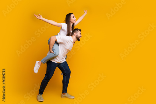 Quadro su tela Full size photo of pretty young male female piggyback flying raise hands wear tr