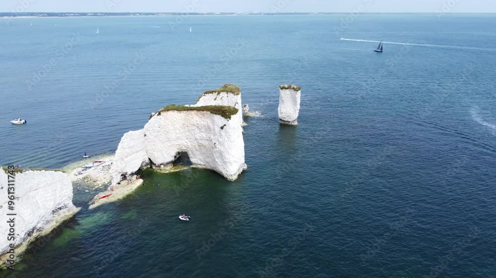 Unrecognizable tourists exploring rock formations of Old Harry Rocks, UK. Aerial circling