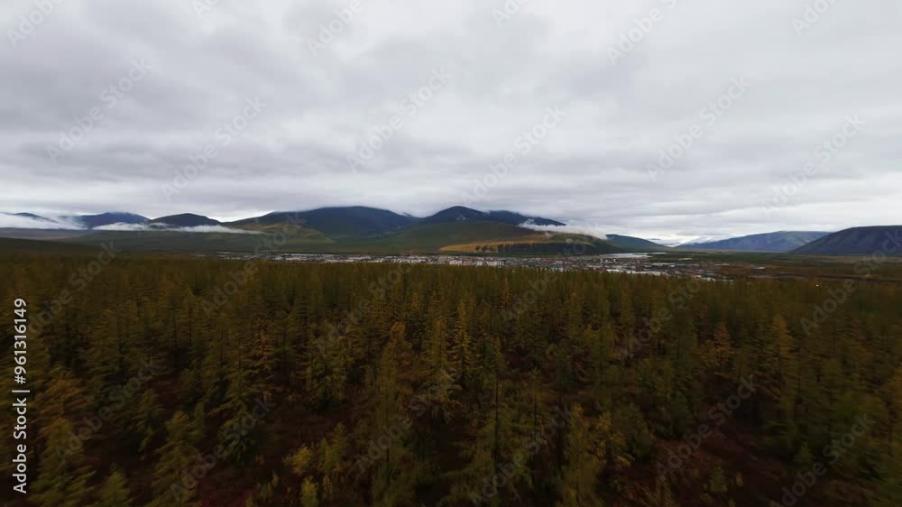 Witness the breathtaking views of Yakutia as a drone captures the vast forests and mountains transitioning into autumn colors amidst cloudy skies. Witness the breathtaking views of Yakutia as a drone captures the vast forests and mountains transitioning into autumn colors amidst cloudy skies.