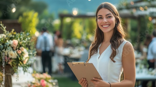Smiling Event Planner Holding Clipboard at Outdoor Wedding Reception with Guests in Background