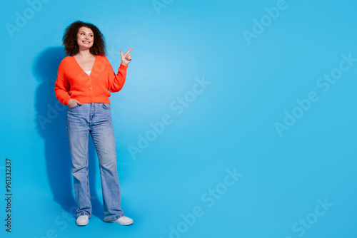 Photo portrait of chevelure hair brasil model woman wearing orange cardigan and jeans indicate finger advet isolated on blue color background photo