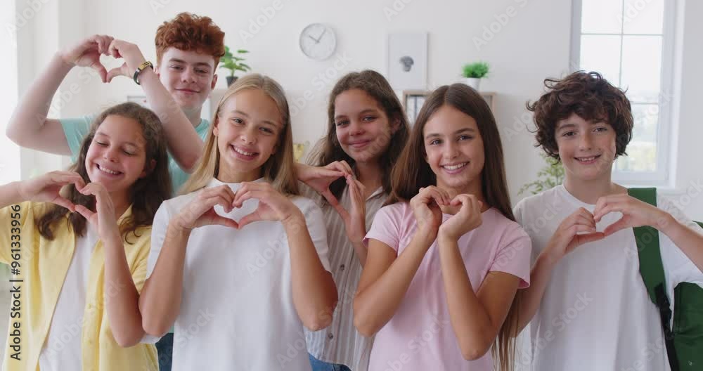 School student friends and classmates girls and boys standing together, looking at camera, smiling, promoting friendly educational environment, showing heart gesture of loving team communication