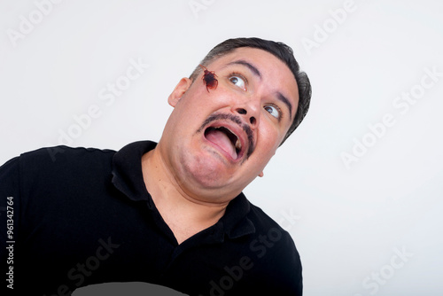 A middle aged man is terrified of a cockroach crawling on his face. Funny scene with an exaggerated scared reaction. Set against a white background. photo