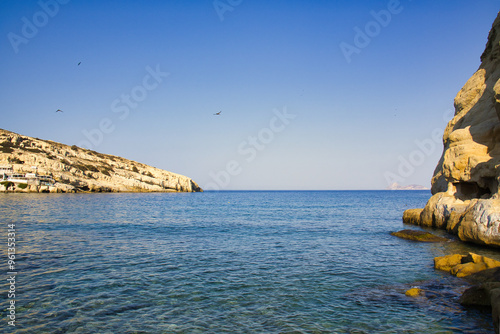Matala bay and beach with caves on the rocks, in morning sun. Crete, Greece 2024