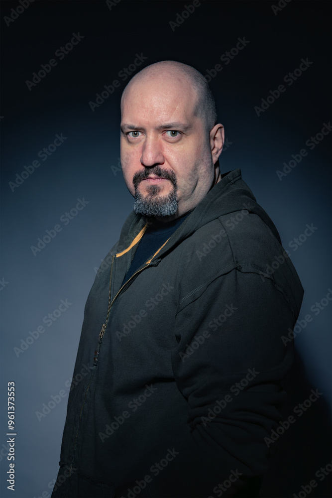 Mature bald man with goatee, dressed in black casual clothes on black background looking at camera with serious expression. Studio photography. Concept of man, maturity and baldness Mature bald man with goatee, dressed in black casual clothes on black background looking at camera with serious expression. Studio photography. Concept of man, maturity and baldness