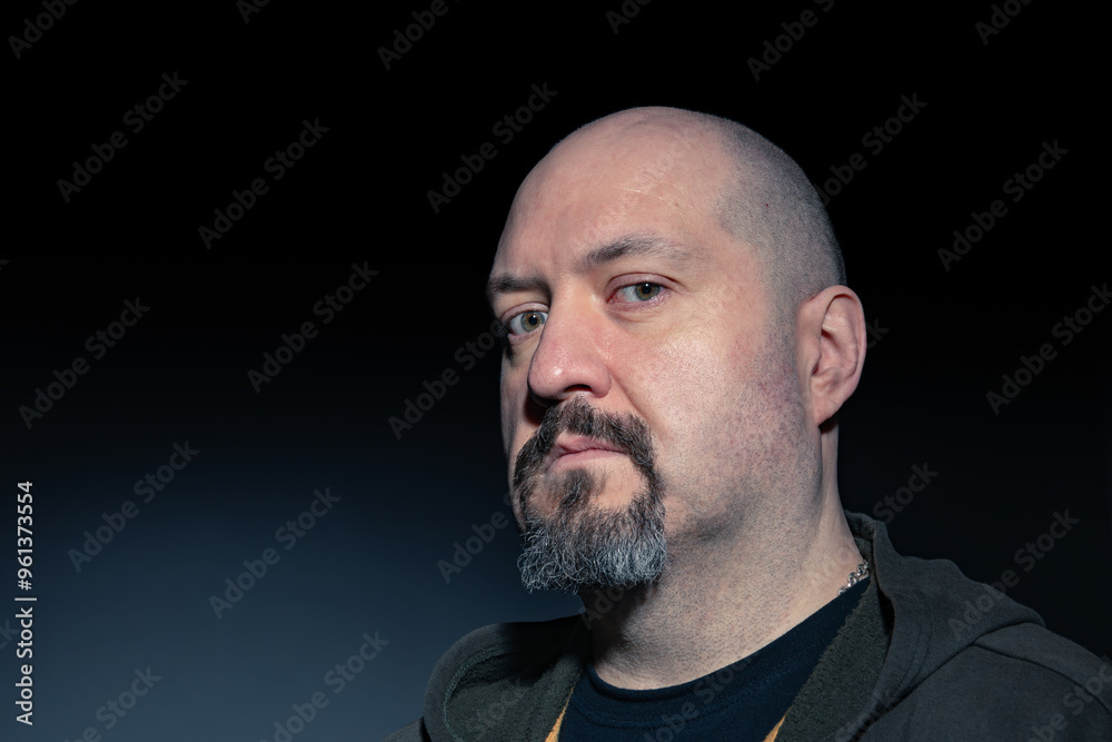 Close-up portrait of a bald and goateed man in his 40's looking at the camera serious and with defiant attitude on black background. Copy space. Concept of seriousness, anger and conflict Close-up portrait of a bald and goateed man in his 40's looking at the camera serious and with defiant attitude on black background. Copy space. Concept of seriousness, anger and conflict