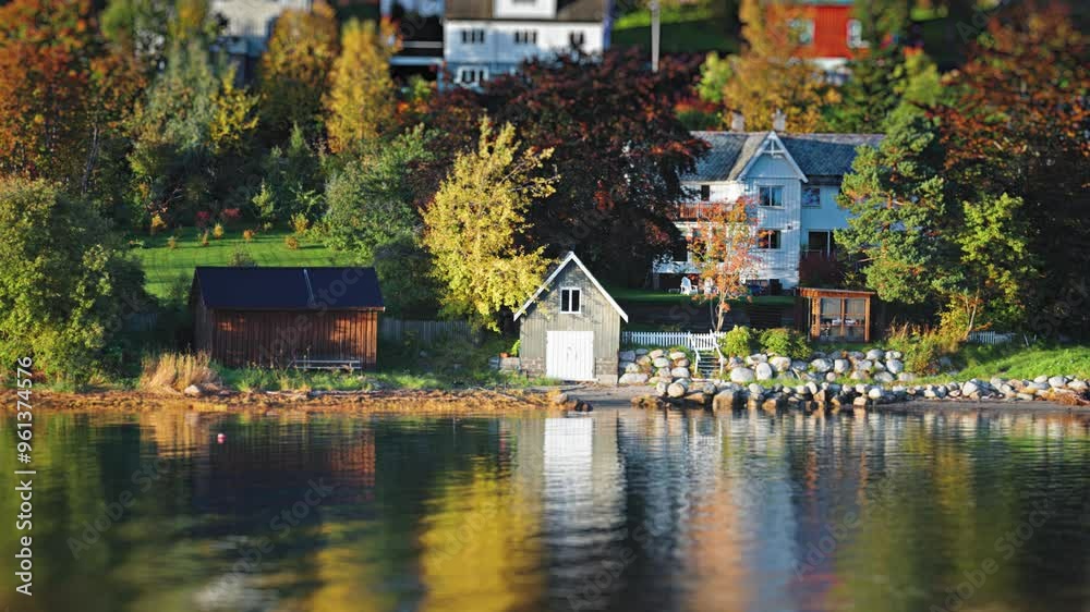 A cluster of homes overlooking a serene lake, set on a lush hillside with trees turning golden in autumn. A cluster of homes overlooking a serene lake, set on a lush hillside with trees turning golden in autumn.