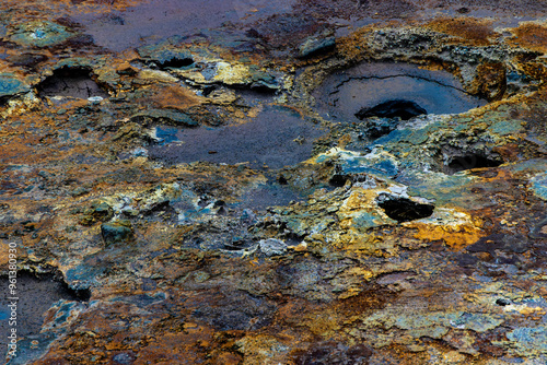 A rocky, muddy area with a lot of holes and puddles photo