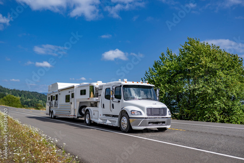 Specialized low profile four doors extended cab white big rig semi truck tractor transporting mobile semi trailer for carry and transporting horses running on the highway road in Columbia Gorge area