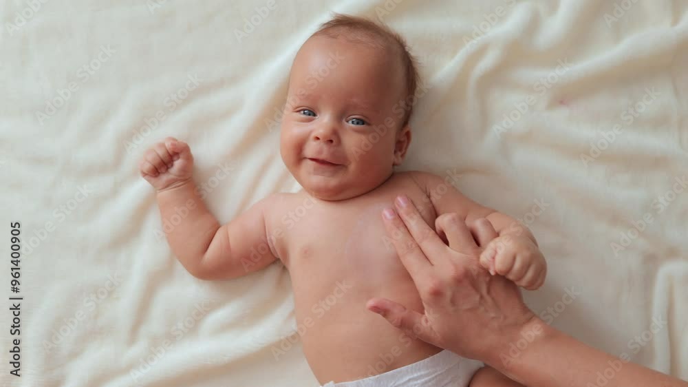 Devoted mother performing relaxing massage on her infant's body focusing on skin hydration taking care of newborn's son well-being gently massaging her infant's chest with hydrating cream Devoted mother performing relaxing massage on her infant's body focusing on skin hydration taking care of newborn's son well-being gently massaging her infant's chest with hydrating cream