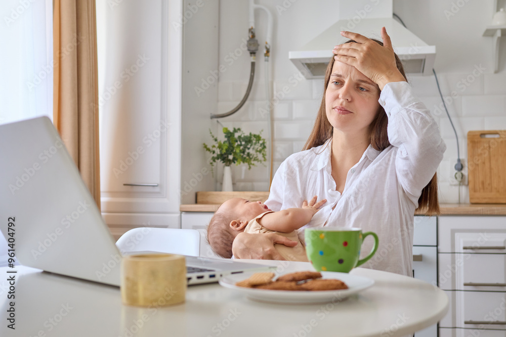 Sick exhausted woman holding newborn child in hands posing at home working on digital tasks and social media doing her remote job during maternity leave suffering headache being overworked Sick exhausted woman holding newborn child in hands posing at home working on digital tasks and social media doing her remote job during maternity leave suffering headache being overworked
