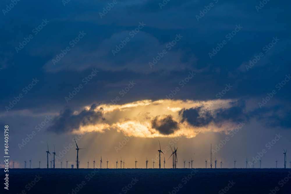 Dark clouds of a thunderstorm with rain falling onto the north sea with silhouettes of wind turbines in the background Dark clouds of a thunderstorm with rain falling onto the north sea with silhouettes of wind turbines in the background