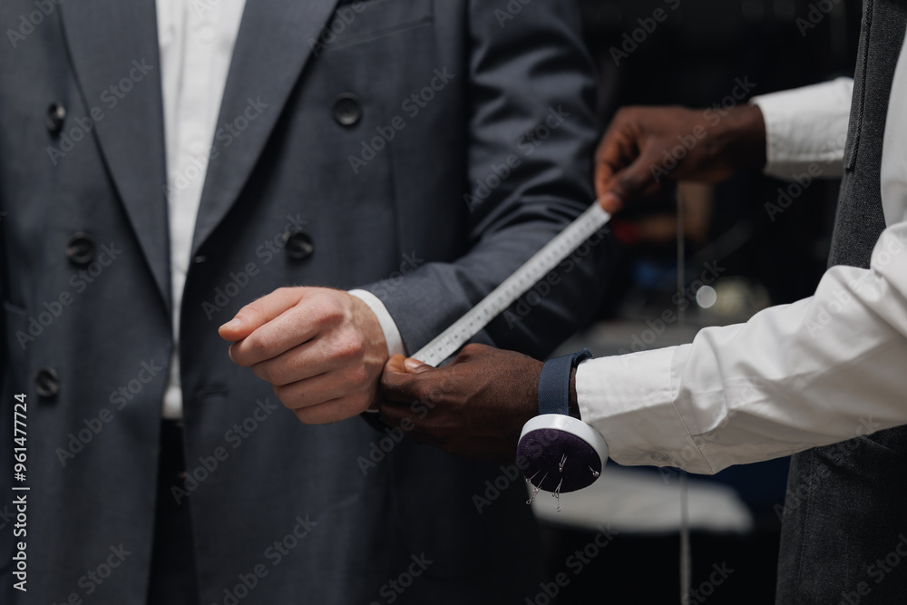 Professional tailor measuring customer for bespoke suit in luxury designer atelier Professional tailor measuring customer for bespoke suit in luxury designer atelier