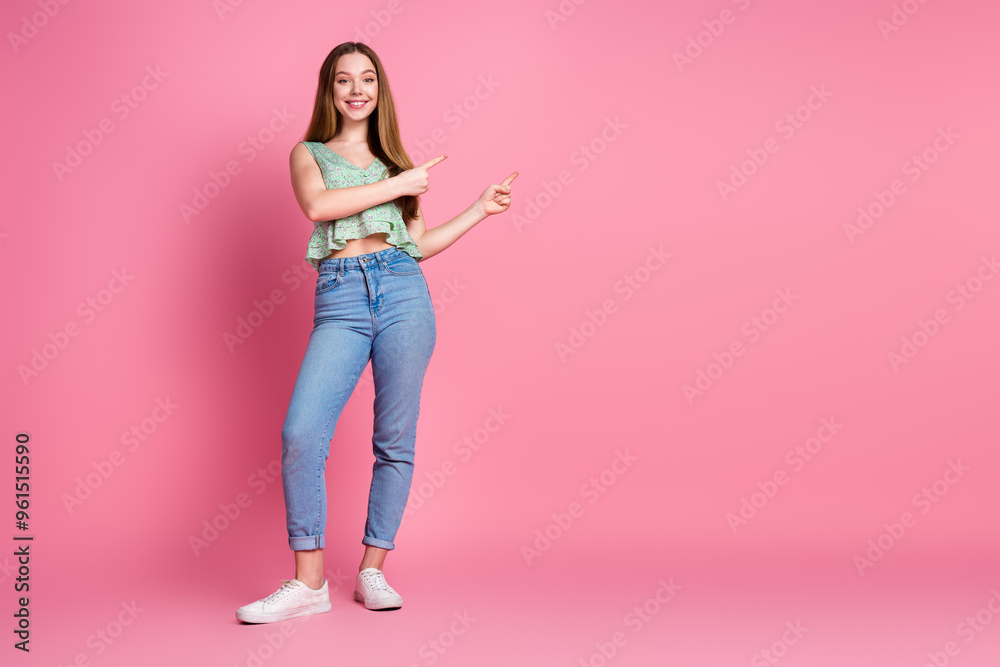 Full size photo of nice young girl indicate fingers empty space wear top isolated on pink color background Full size photo of nice young girl indicate fingers empty space wear top isolated on pink color background