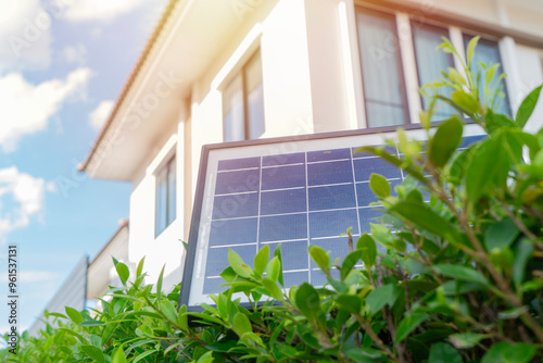 Fotografie Mini solar cell panel setting on top of tree wall over house and blue sky