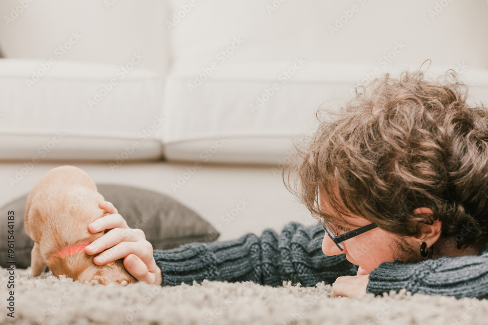 Young man relaxing at home playing with puppy dog Young man relaxing at home playing with puppy dog
