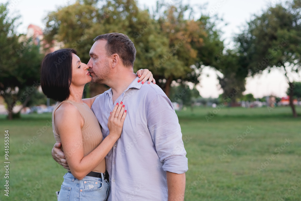 A happy smiling couple walking, hugging and kissing in park on late summer sunset A happy smiling couple walking, hugging and kissing in park on late summer sunset