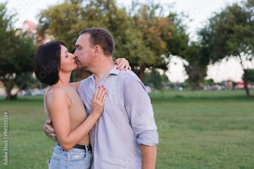 A happy smiling couple walking, hugging and kissing in park on late summer sunset photo