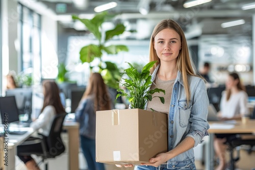 Female employee unpacking box with personal belongings at workplace on first working day in shared office, excited newcomer to start new job concept with a smile on her face. photo