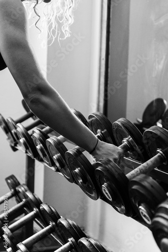 A female picks up a dumbbell in the gym
