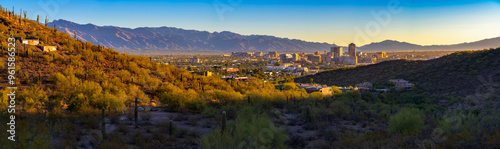 Photos Panoramic view of Tucson, Arizona, with downtown buildings surrounded by desert landscape, saguaro cacti, and Santa Catalina Mountains at sunrise