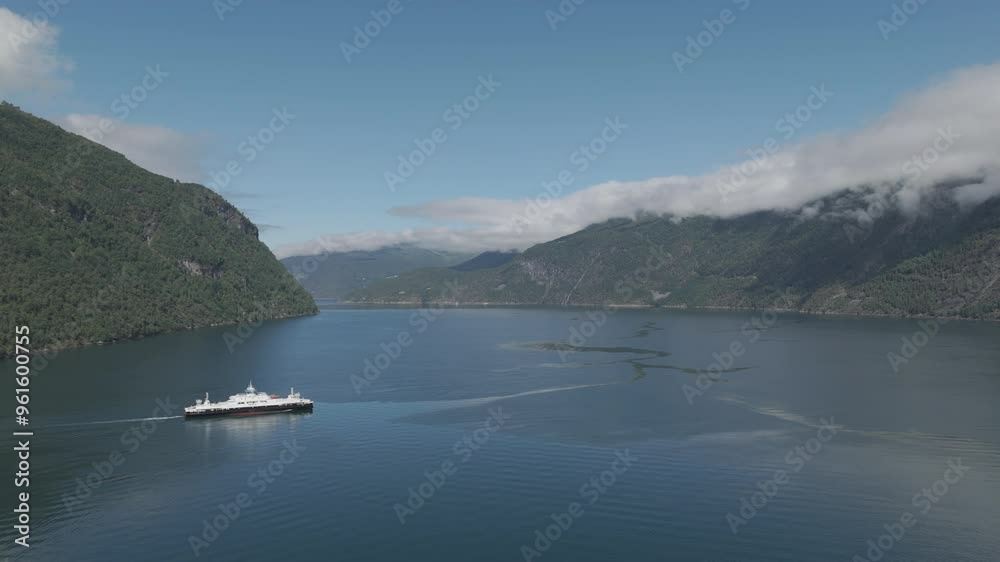 Drone shot of a car Ferry crossing the Fjord in Norway on a sunny day with clear water and reflections and mountains in the background with clouds between them LOG Drone shot of a car Ferry crossing the Fjord in Norway on a sunny day with clear water and reflections and mountains in the background with clouds between them LOG