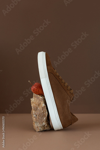 Still life of brown men's minimalist boots with white sole on beige and brown background. Autumn concept photo