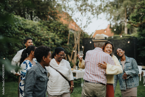 Happy family members greeting each other during social gathering at garden party photo