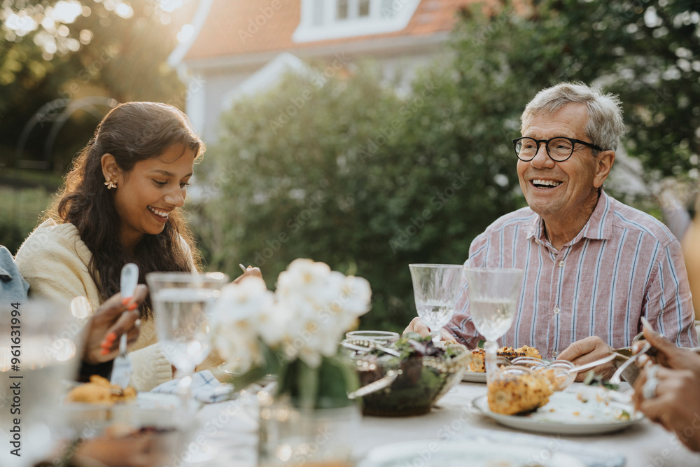 Active senior man having lunch with teenage family member at garden party Active senior man having lunch with teenage family member at garden party