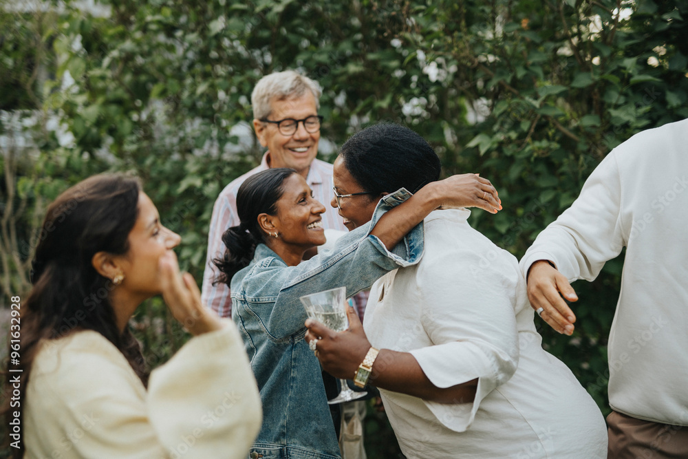 Happy female family members greeting each other at social gathering in back yard Happy female family members greeting each other at social gathering in back yard