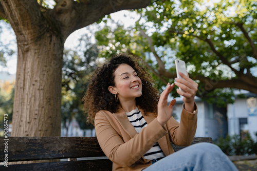 Wallpaper Mural pretty curly smiling woman walking in city street in stylish jacket, using smartphone Torontodigital.ca