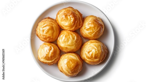 Golden puff pastries arranged on a white plate against a clean white background photo