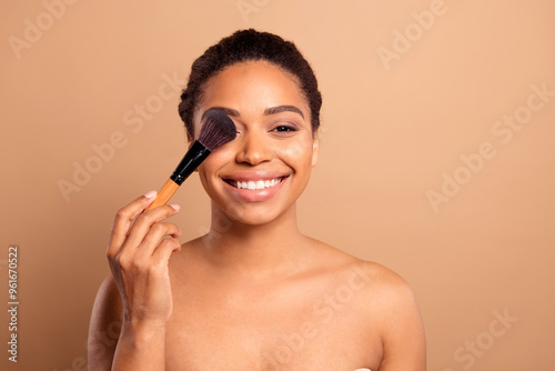 Photo of gorgeous cheerful woman apply make up brush naked shoulders isolated on beige pastel color background