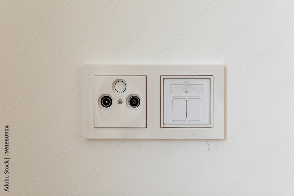 White Electrical Outlet and Light Switch on a White Wall White Electrical Outlet and Light Switch on a White Wall