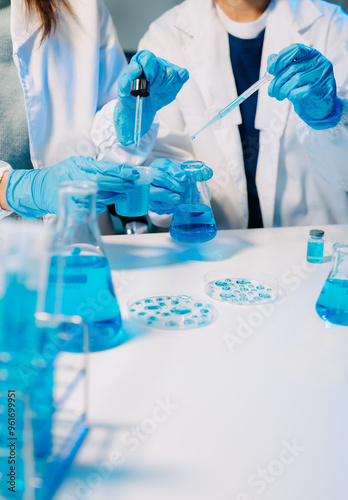 scientists in lab coats conducting research, handling glassware, and working with chemicals