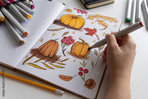 Hand holding marker while drawing autumn illustration