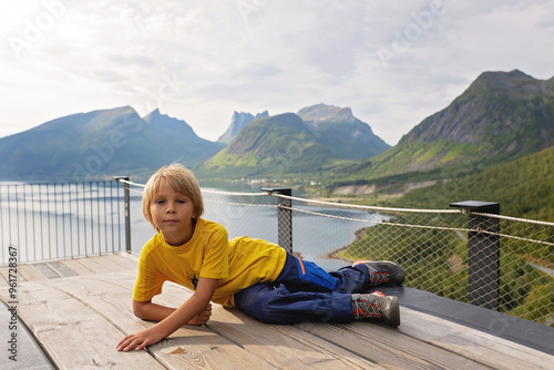 Children, standing on the edge of a 44 meter long viewing platform, overlooking the water of Bergsfjord, enjoying the view on Senja island, Norway photo