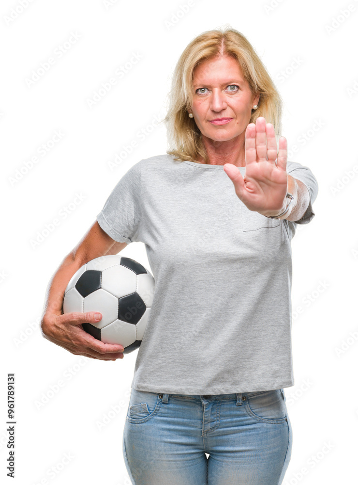 Middle age blonde woman holding soccer football ball over isolated background with open hand doing stop sign with serious and confident expression, defense gesture Middle age blonde woman holding soccer football ball over isolated background with open hand doing stop sign with serious and confident expression, defense gesture