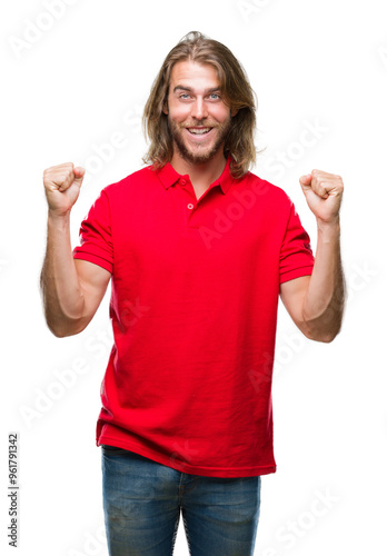 Young handsome man with long hair over isolated background celebrating surprised and amazed for success with arms raised and open eyes. Winner concept.