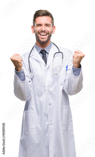 Young handsome doctor man over isolated background very happy and excited doing winner gesture with arms raised, smiling and screaming for success. Celebration concept.